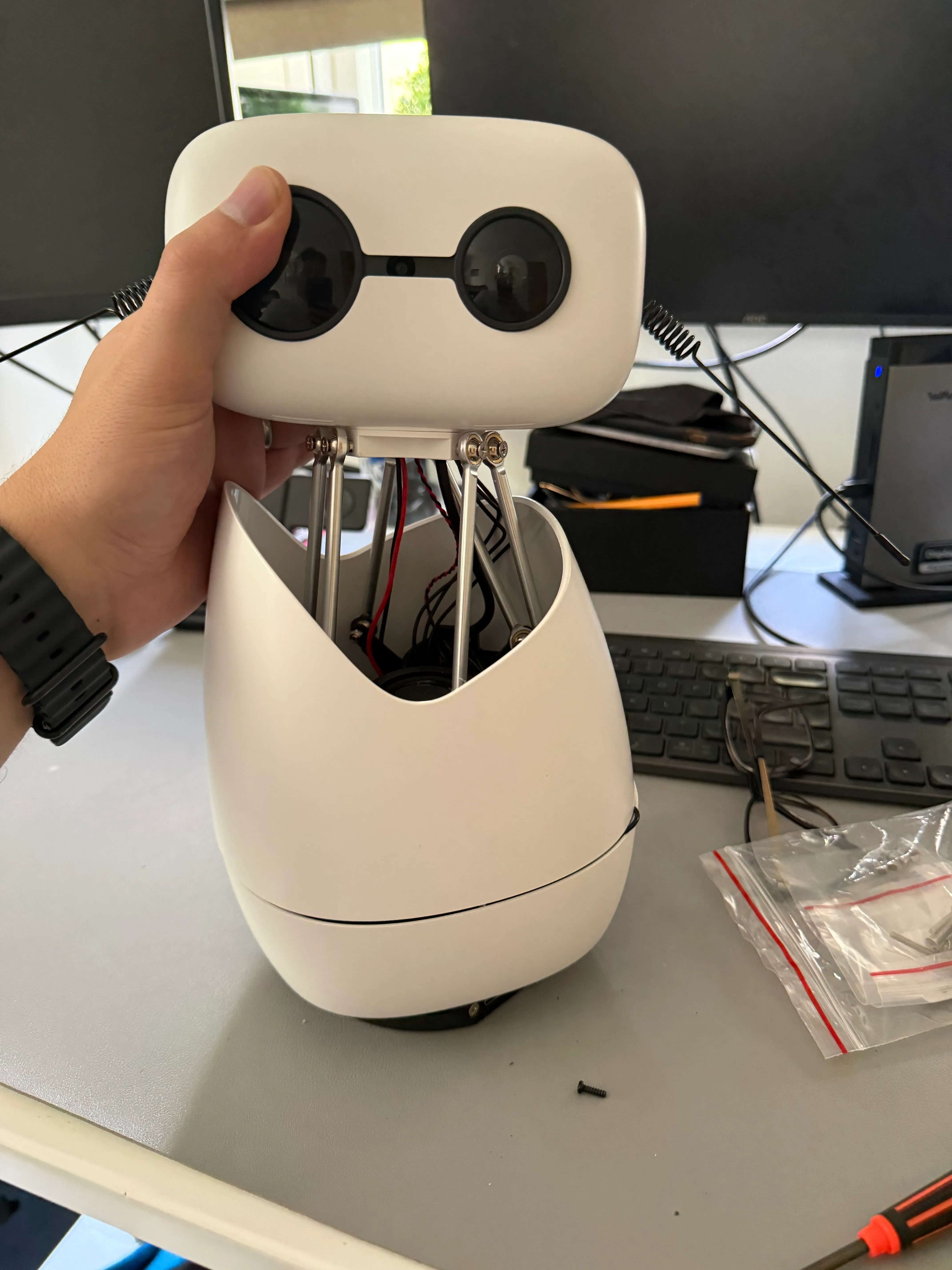 Attaching Mycroft's head at the desk: the robot upright, eyes level, mid-assembly